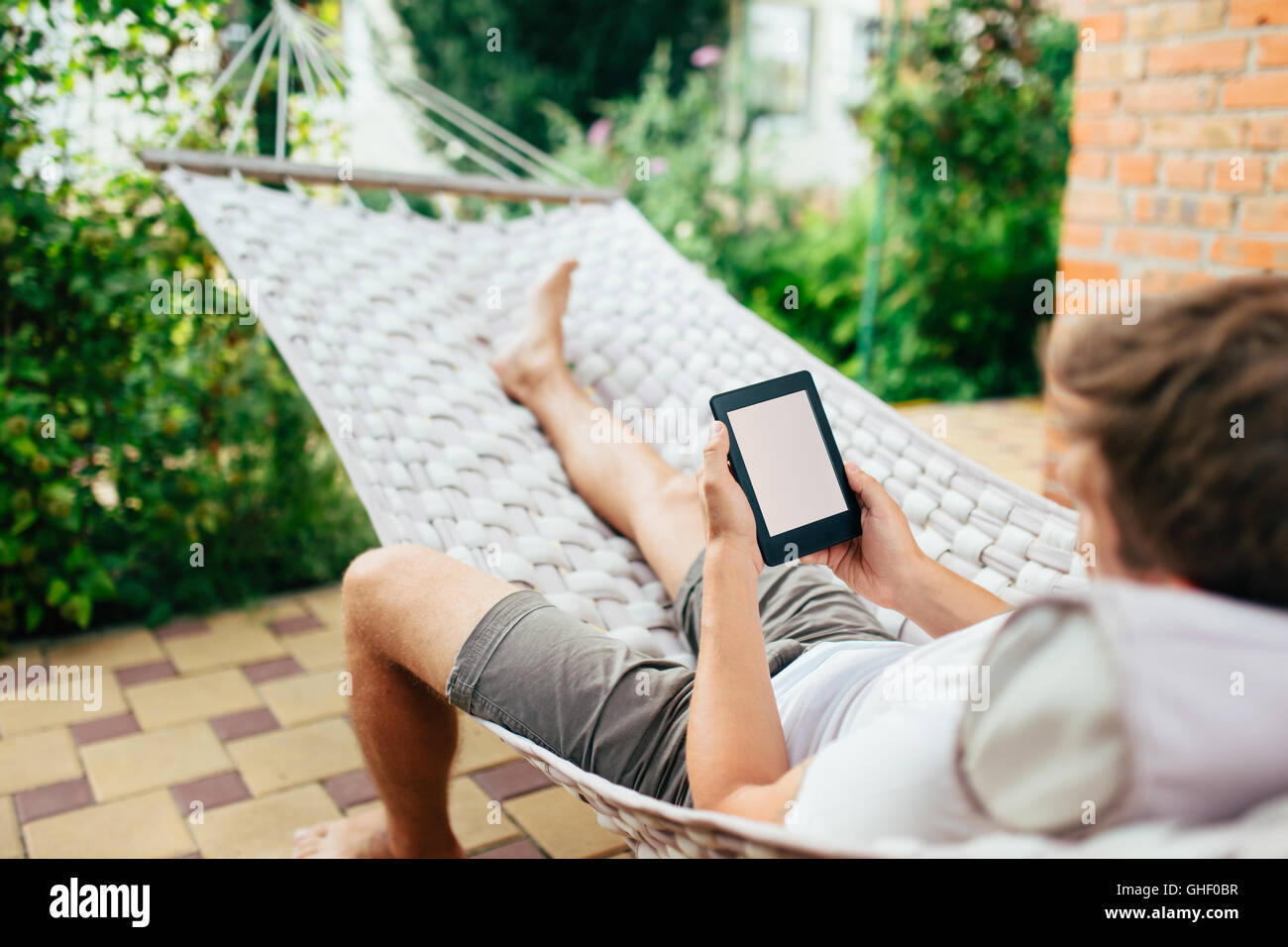 Man using e-book or tablet computer while relaxing in a hammock Stock Photo