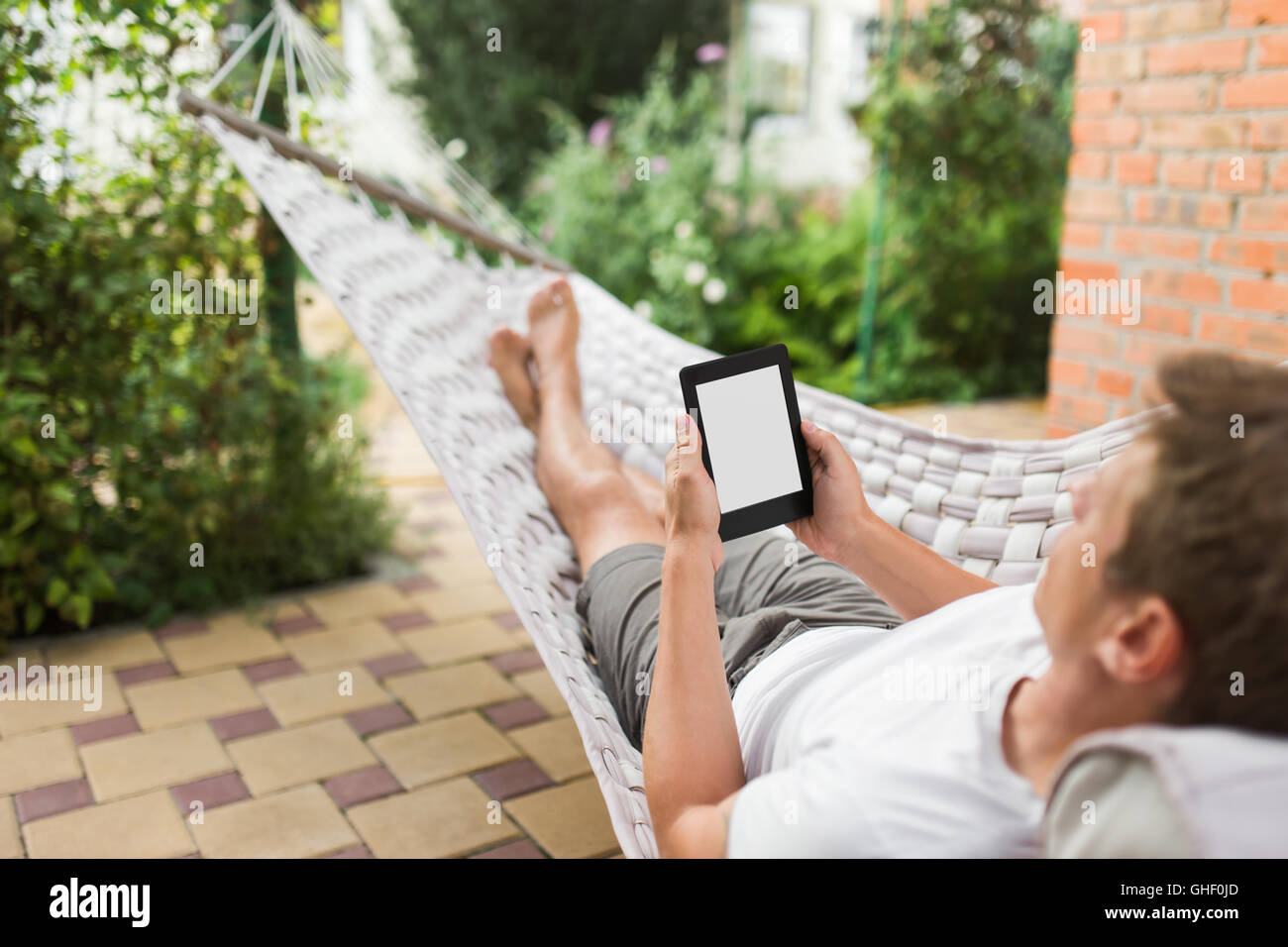 Man using e-book or tablet computer while relaxing in a hammock Stock Photo