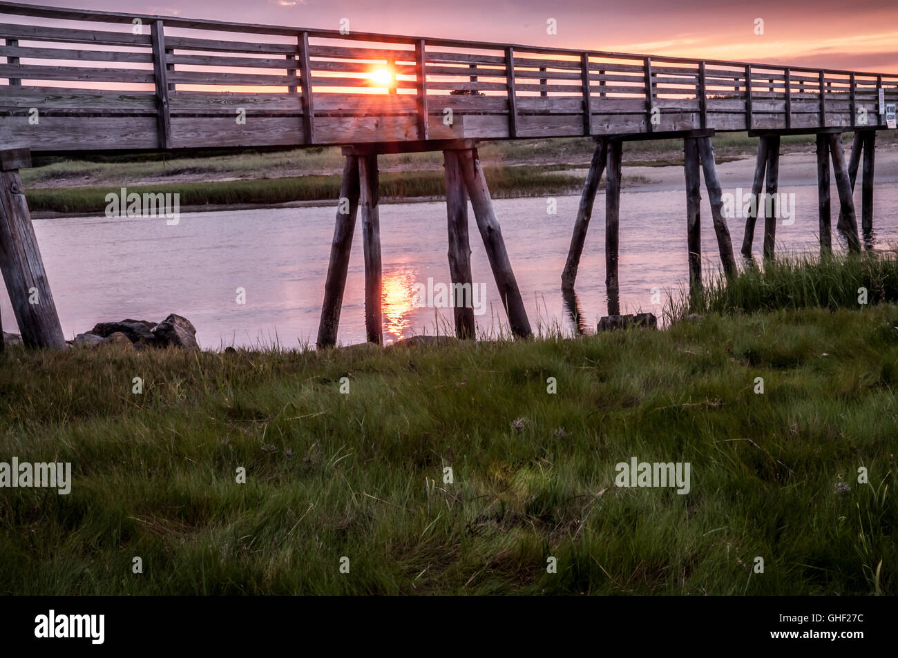 The Sun comes up on the other side of the bridge giving off its glow. It looks like it is making its way across this old bridge. Stock Photo