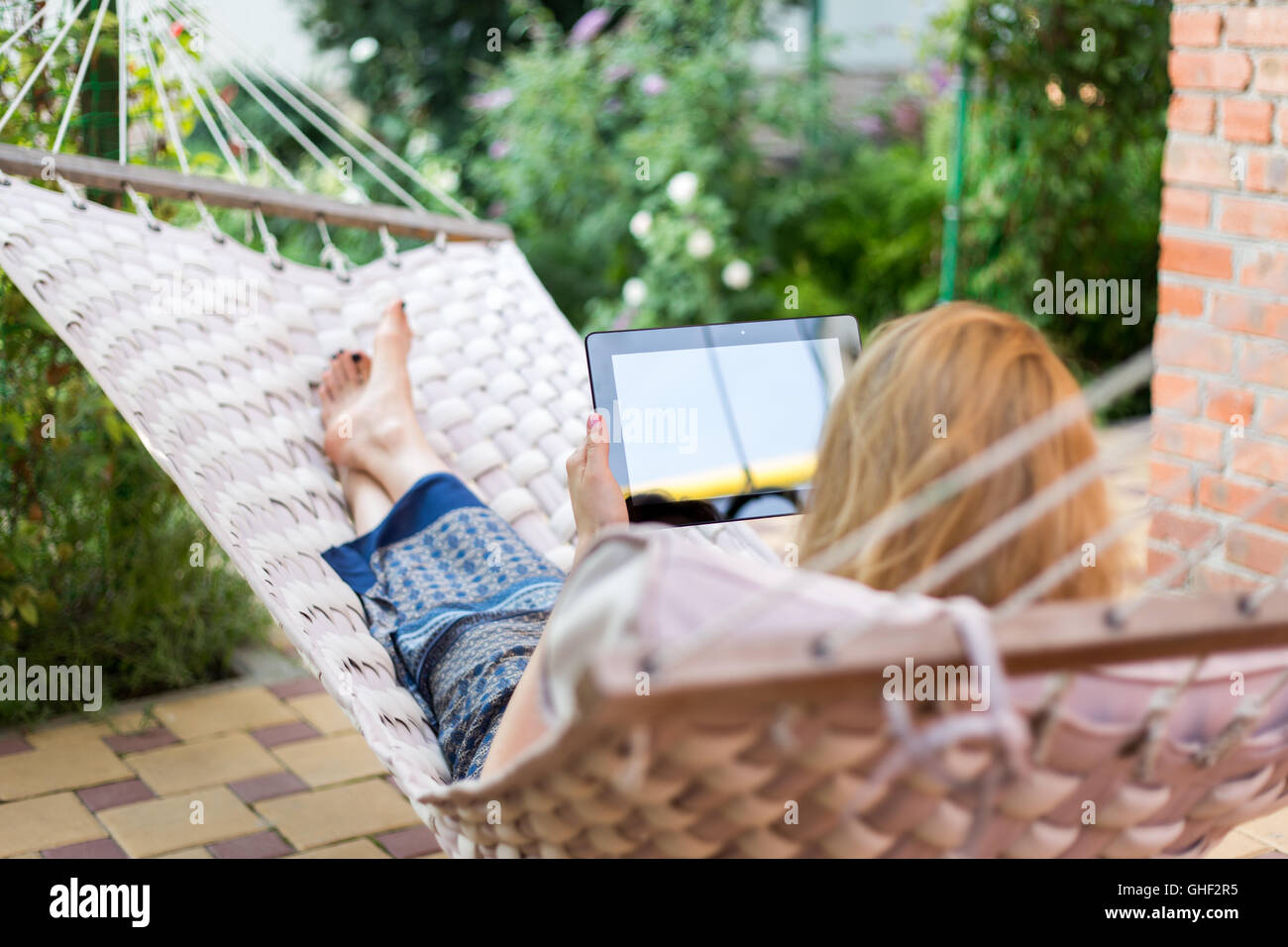 Woman using tablet computer while relaxing in a hammock Stock Photo