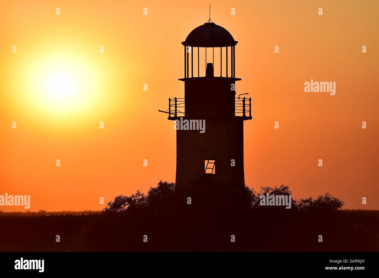 Abandoned old and weathered lighthouse at sunset on a river Stock Photo