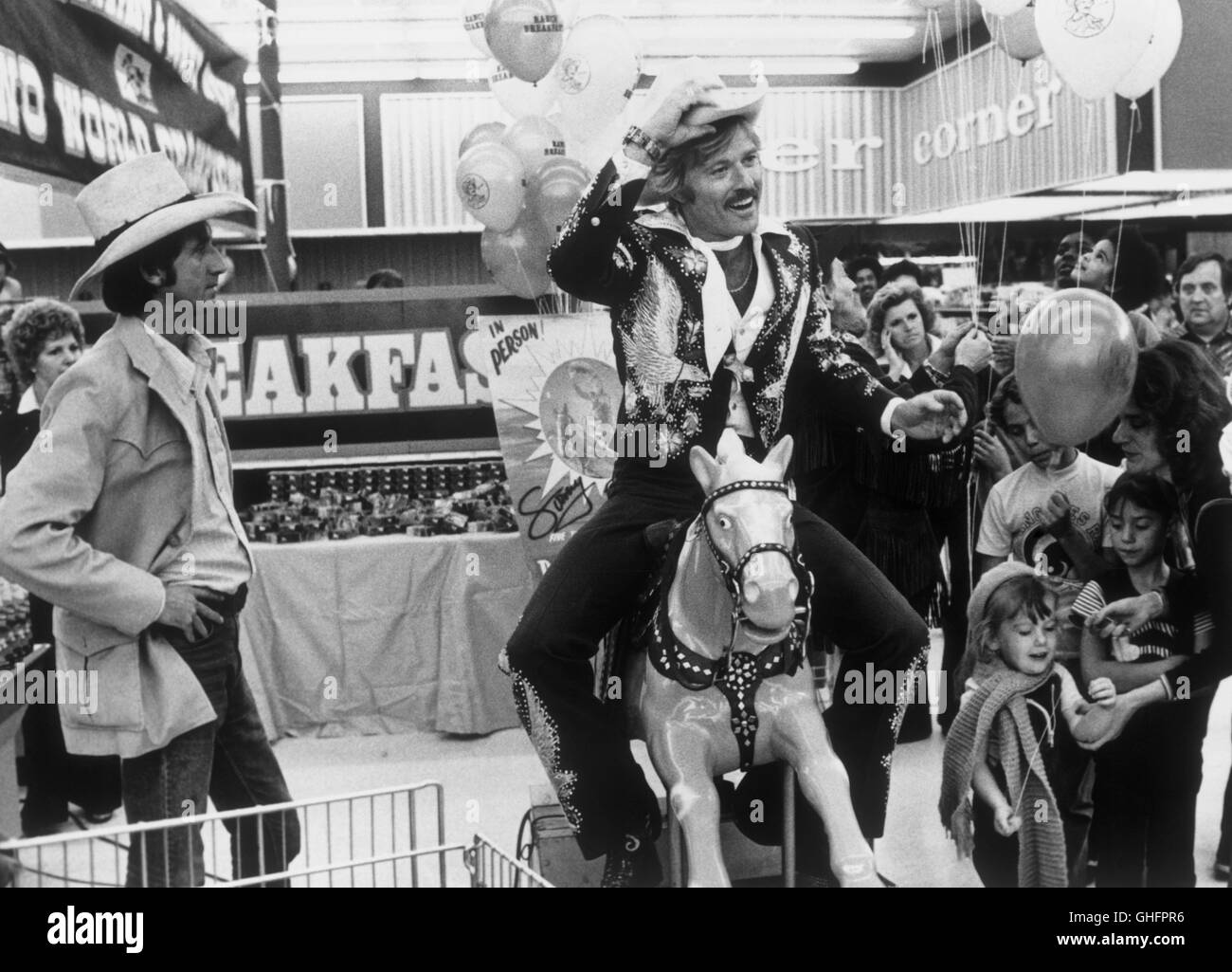 Proud Ex-rodeo cowboy Sonny Steele (ROBERT REDFORD) reduced to huckstearing cereal, opens a supermarket astride a mechanical horse while Leroy (TIMOTHY SCOTT) looks on. Regie: Sydney Pollack Stock Photo