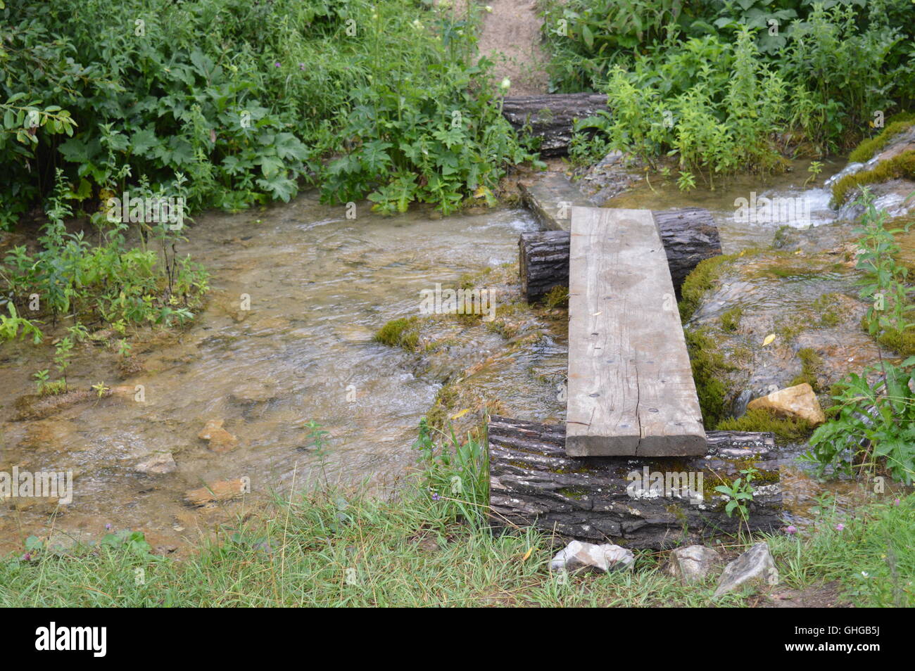 Makeshift wooden bridge over a watercourse Stock Photo
