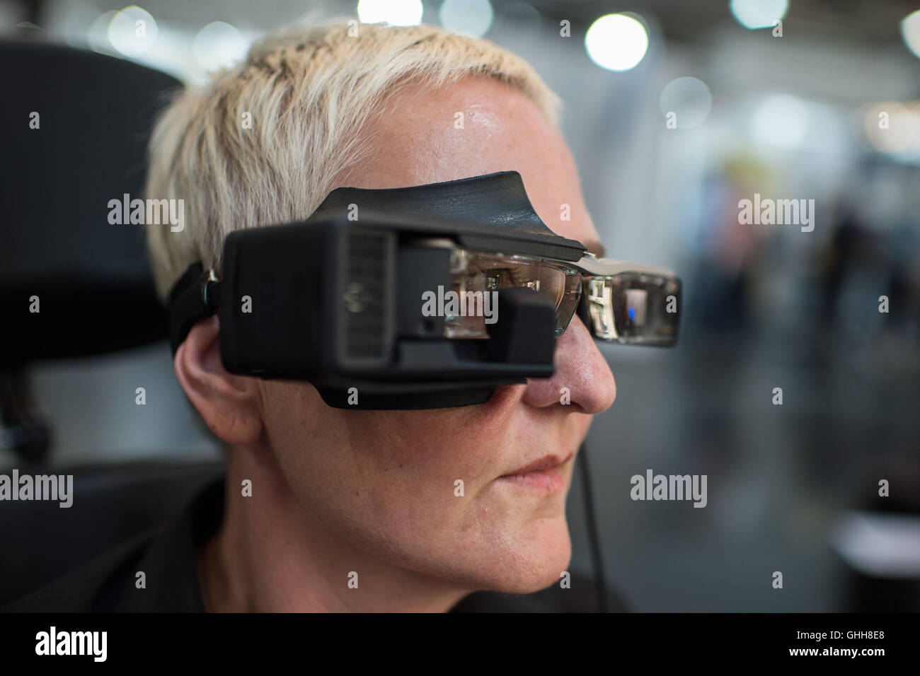 Duesseldorf, Germany. 28th Sep, 2016. A woman wearing the so-called 'Eye Speak' glasses during the opening of the international care fair 'Rheacare' in Duesseldorf, Germany, 28 September 2016. The glasses are equipped with a screen and a virtual keyboard. An inbuild camera recognises the eye movement of the person wearing the glasses, allowing the selection of letters on the monitor. The glasses are said to be a communication system for people with extremely limited movement and communication. The fair runs until 1 October 2016. PHOTO: WOLFRAM KASTL/dpa/Alamy Live News Stock Photo