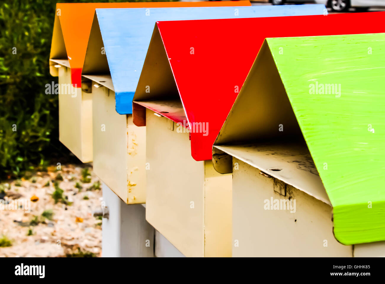 Row of four mailboxes, or letterboxes, with colorful lime green, red