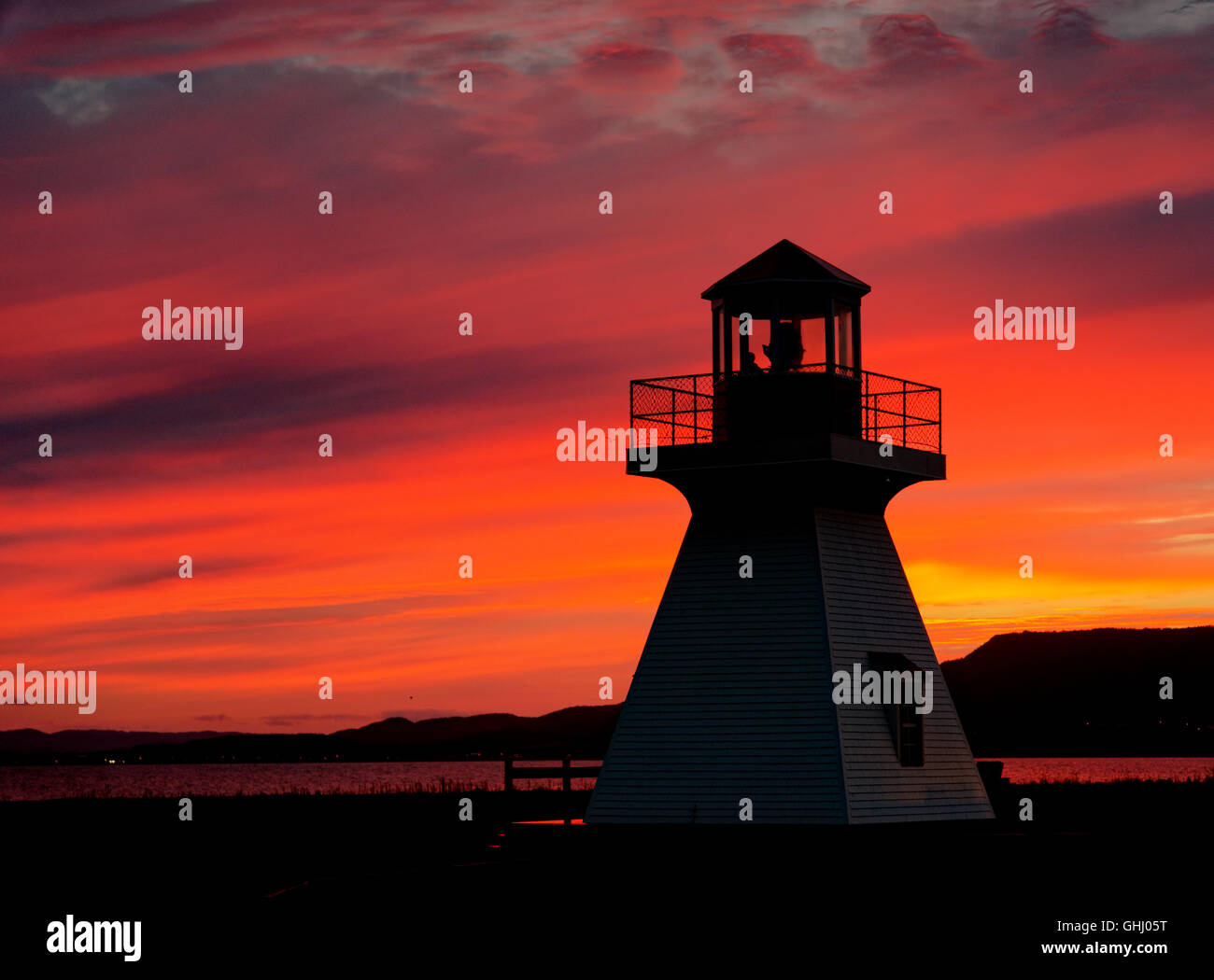 A fiery sunset behind the lighthouse at Carleton in Gaspesie, Quebec, Canada Stock Photo