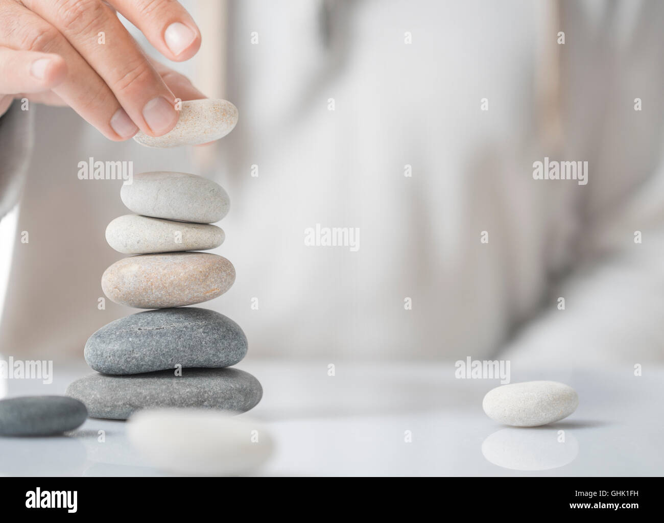 Horizontal image of a man stacking pebbles on a table with copyspace for text. Concept of personal development or self realizati Stock Photo