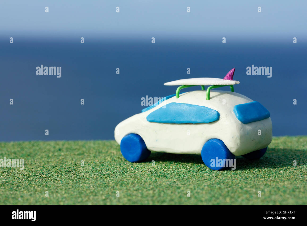 Plasticine Car and Balsa Wood Surfboard by the Ocean Stock Photo
