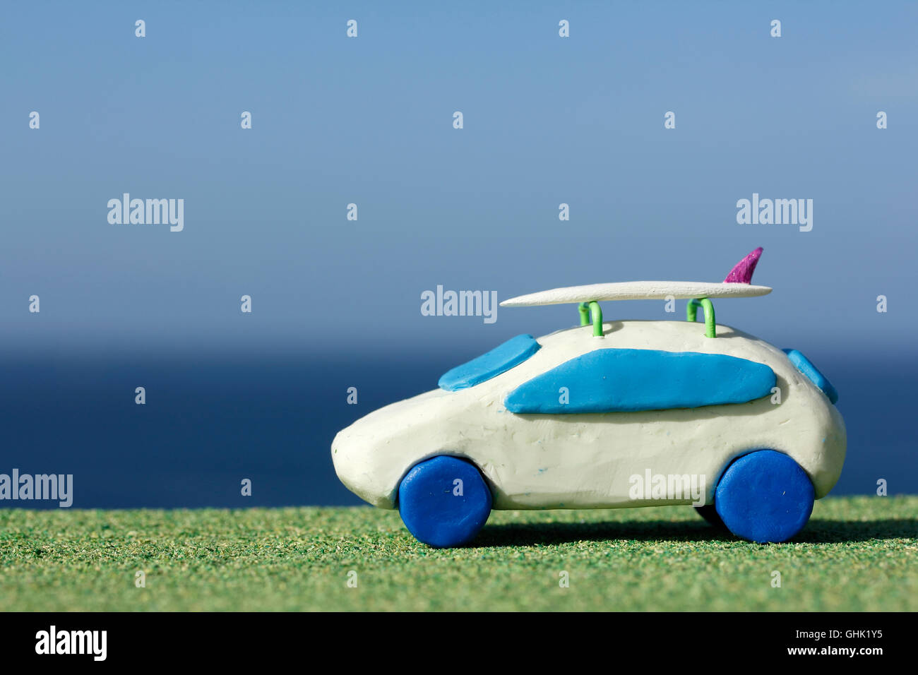 Plasticine Car and Balsa Wood Surfboard by the Ocean Stock Photo