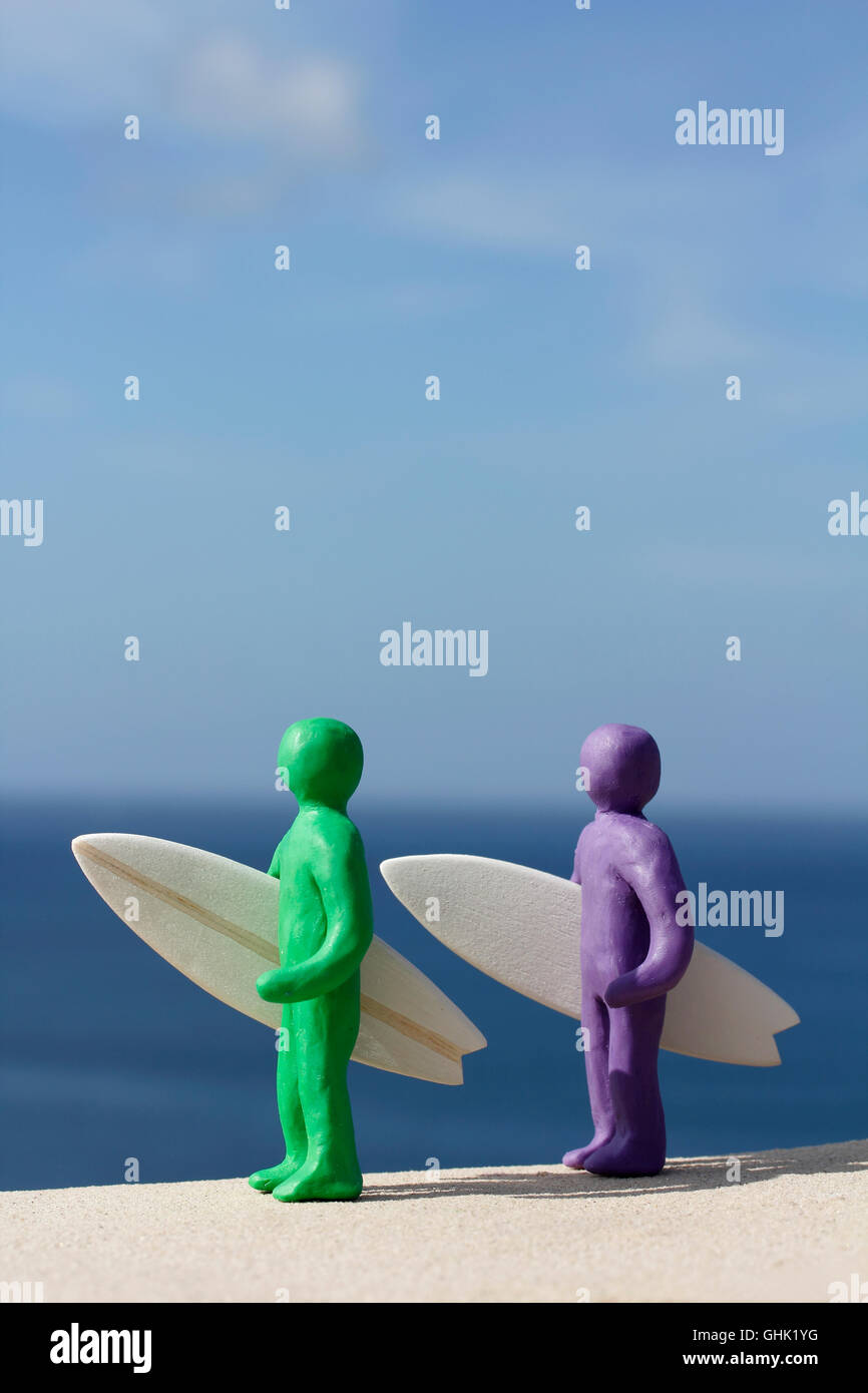 Plasticine people with balsa wood surfboards by the Ocean. Stock Photo