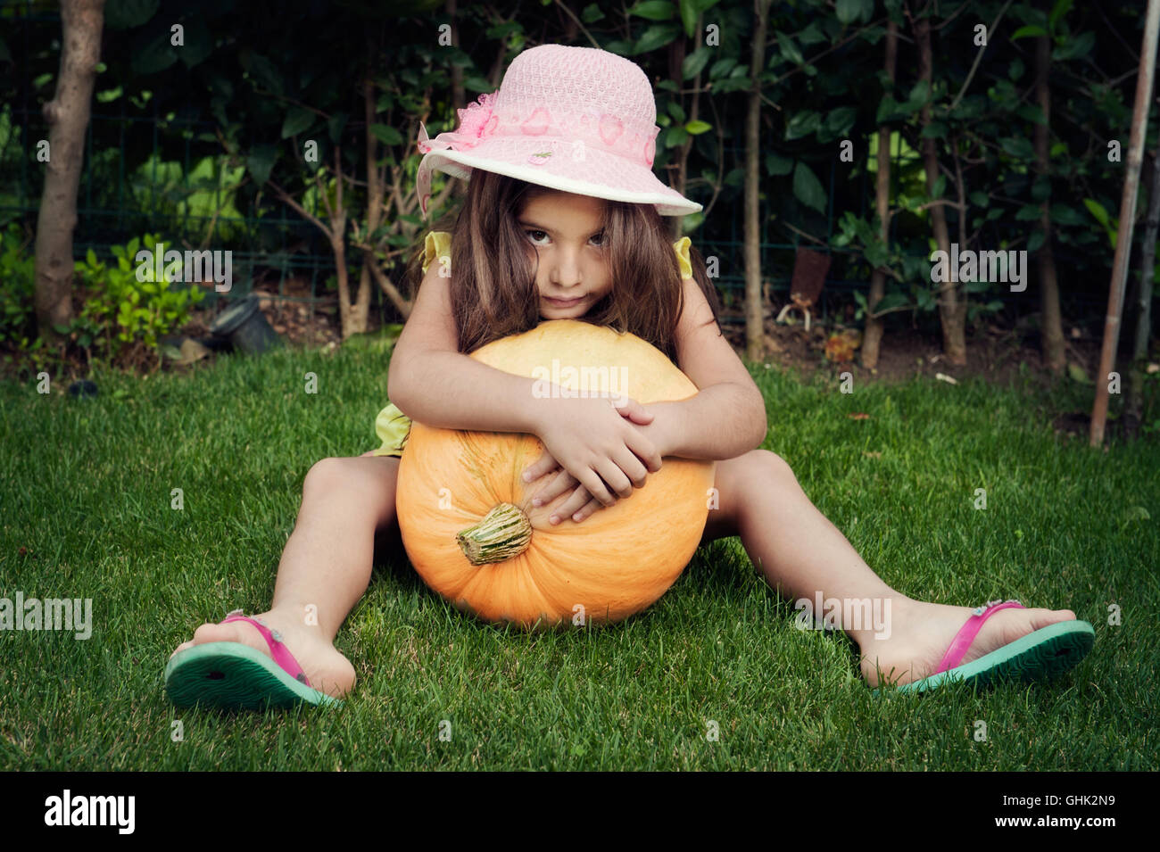 Portrait of Little Girl with pumpkin sitting on grass Stock Photo - Alamy