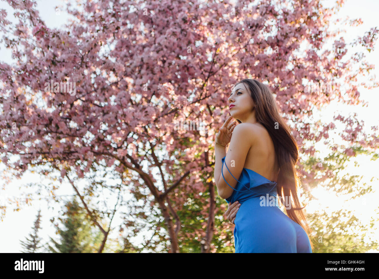 Back view of a beautiful young woman dressed in blue overalls standing ...
