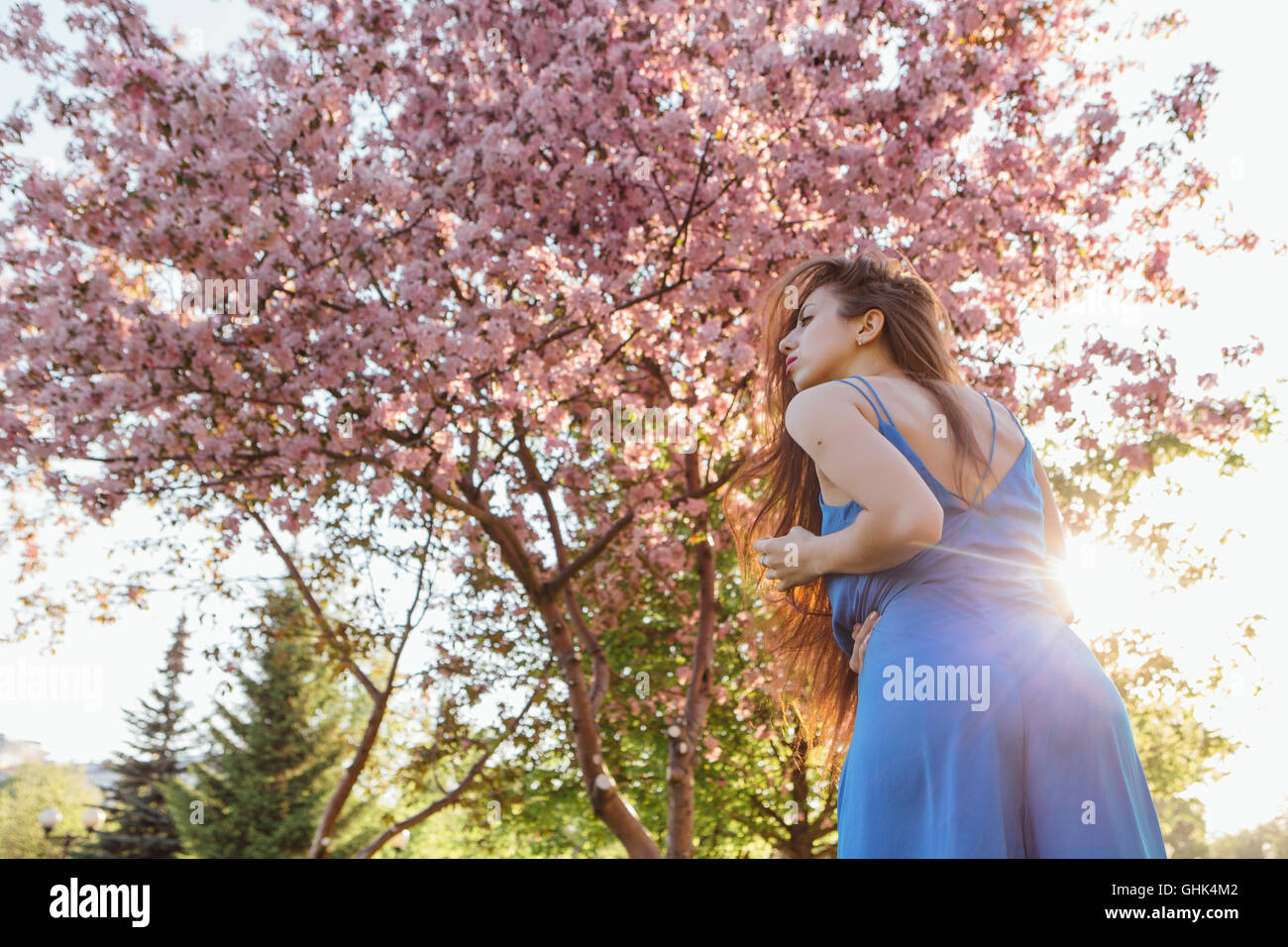 Back view of a beautiful young woman dressed in blue overalls standing ...