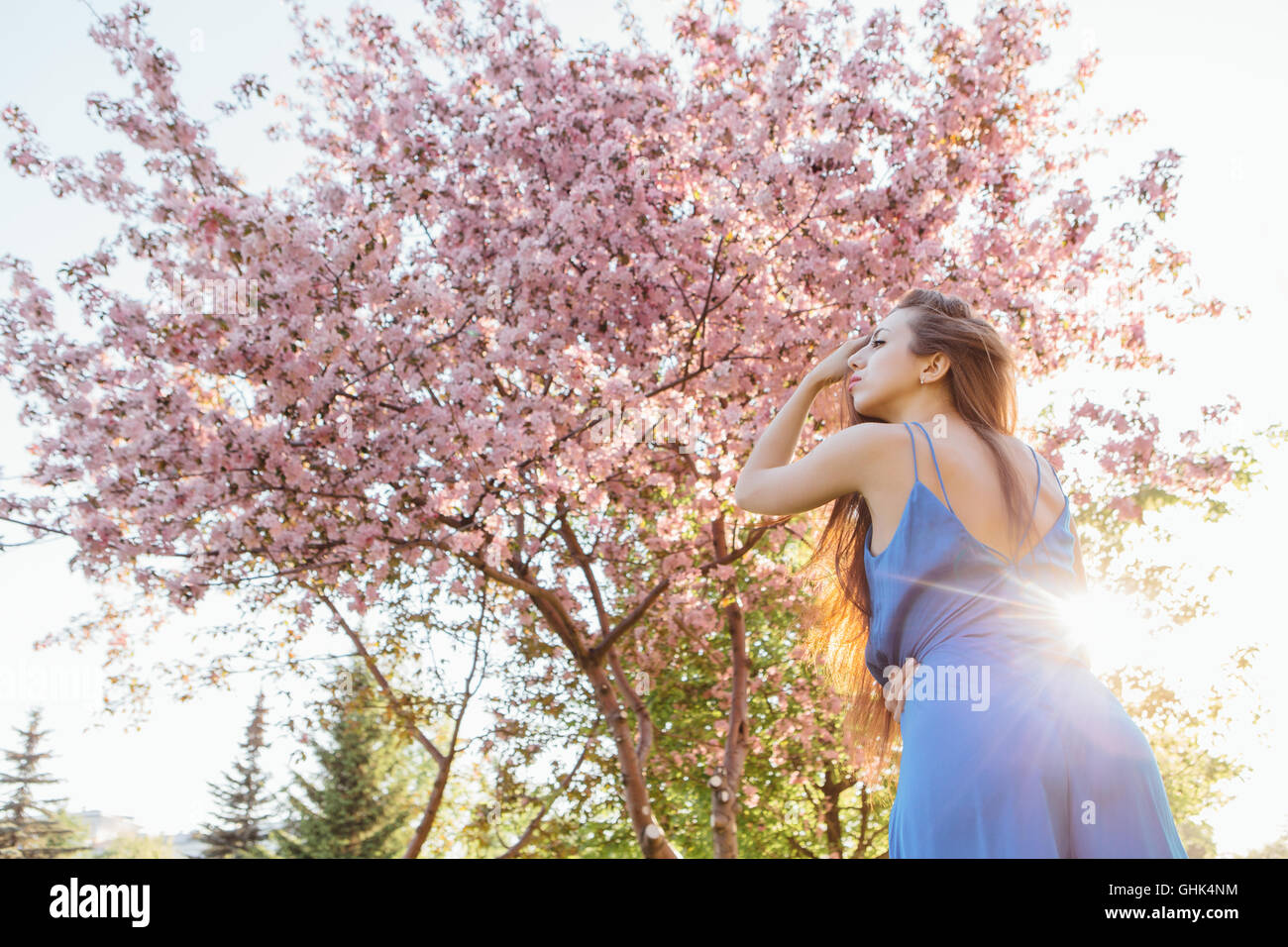 Back view of a beautiful young woman dressed in blue overalls standing ...