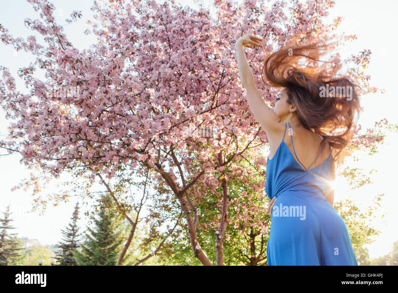 Back view of a beautiful young woman dressed in blue overalls standing ...