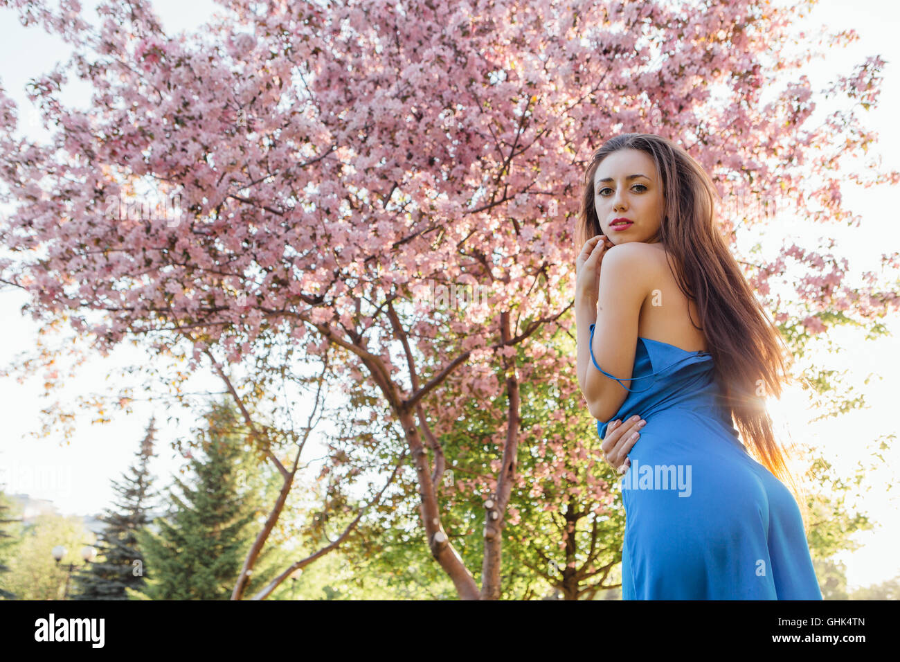 Back view of a beautiful young woman dressed in blue overalls standing ...