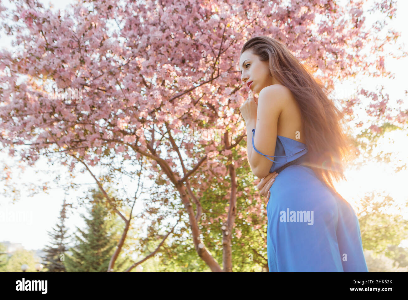 Back view of a beautiful young woman dressed in blue overalls standing ...