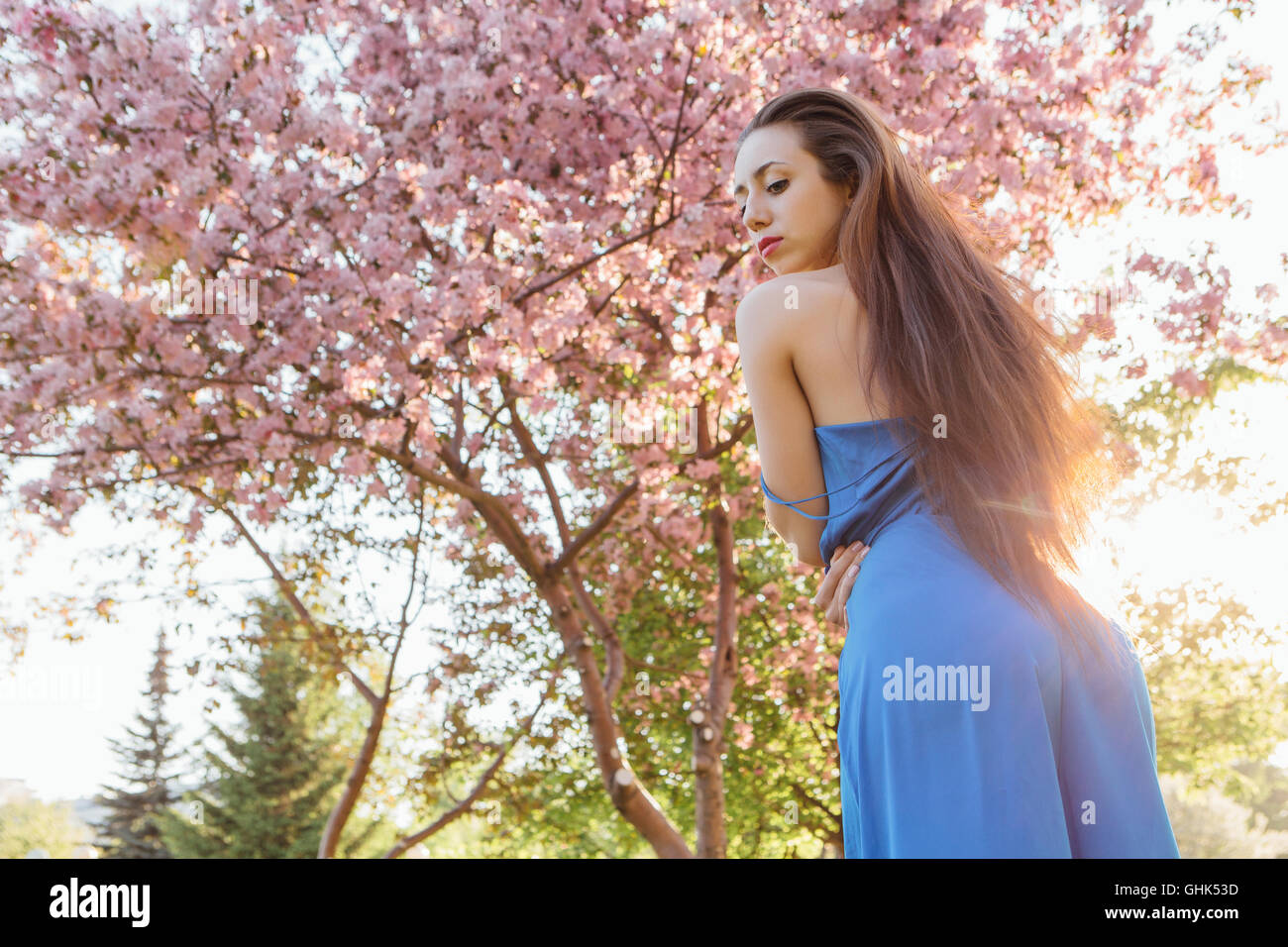 Back view of a beautiful young woman dressed in blue overalls standing ...
