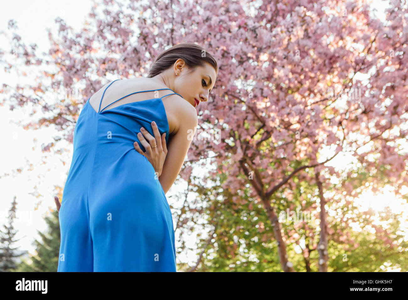 Back view of a beautiful young woman dressed in blue overalls standing ...