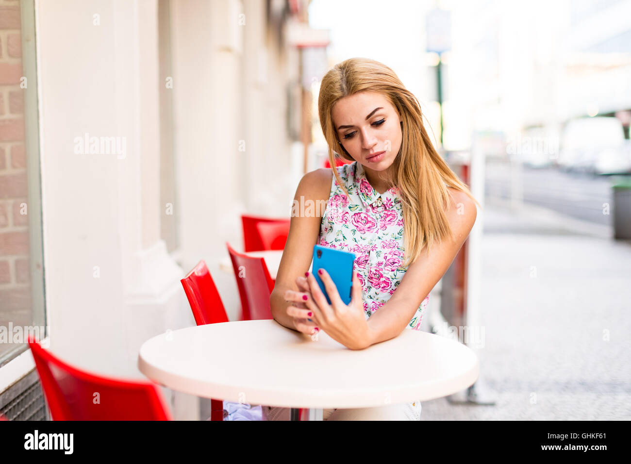 Young woman in street cafe with cellphone Stock Photo