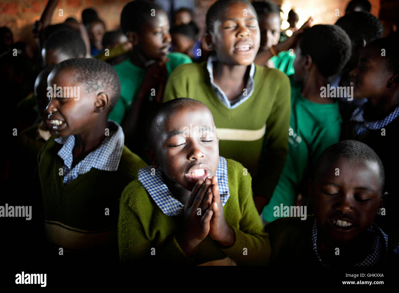 African school children in rural Uganda take a moment during morning assembly to prayer during morning chapel Stock Photo