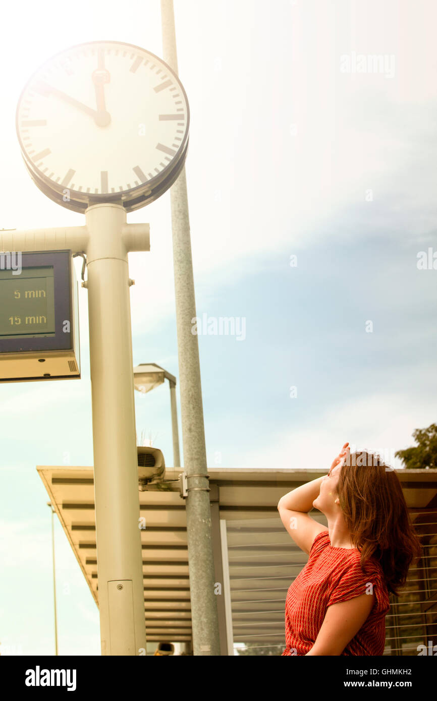 young woman looking at the clock at train station Stock Photo