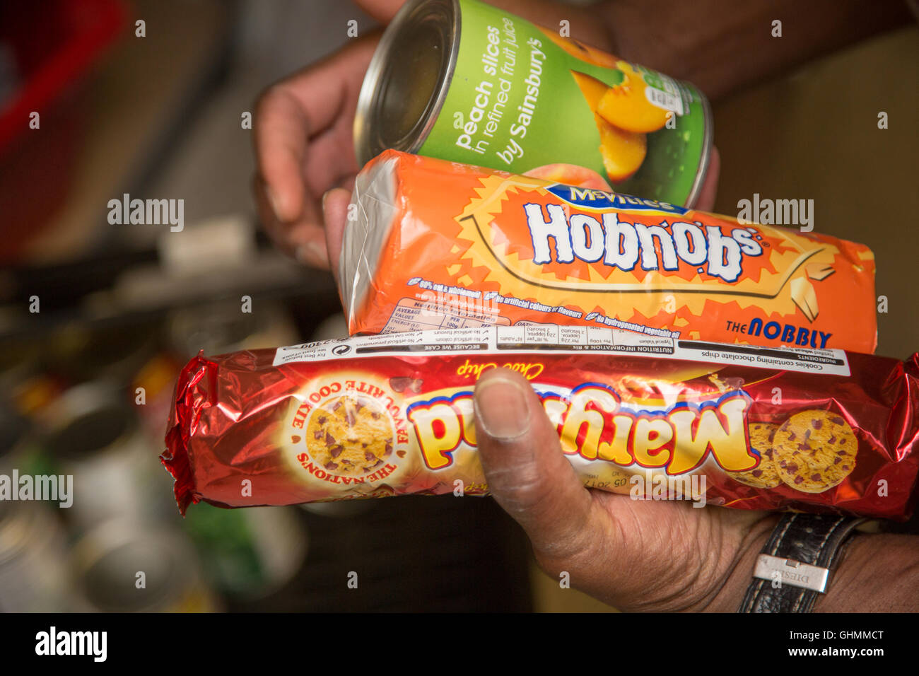 A man collecting a biscuits and tins from a shelf at the North Paddington Foodbank, London Stock Photo