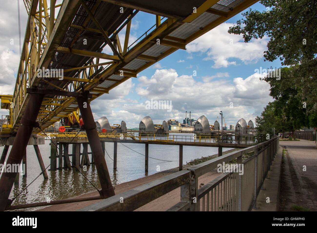 Asphalt conveyor belt on River Thames London delivering gravel to tarmac  factory on riverbank with Thames Barrier in background Stock Photo - Alamy