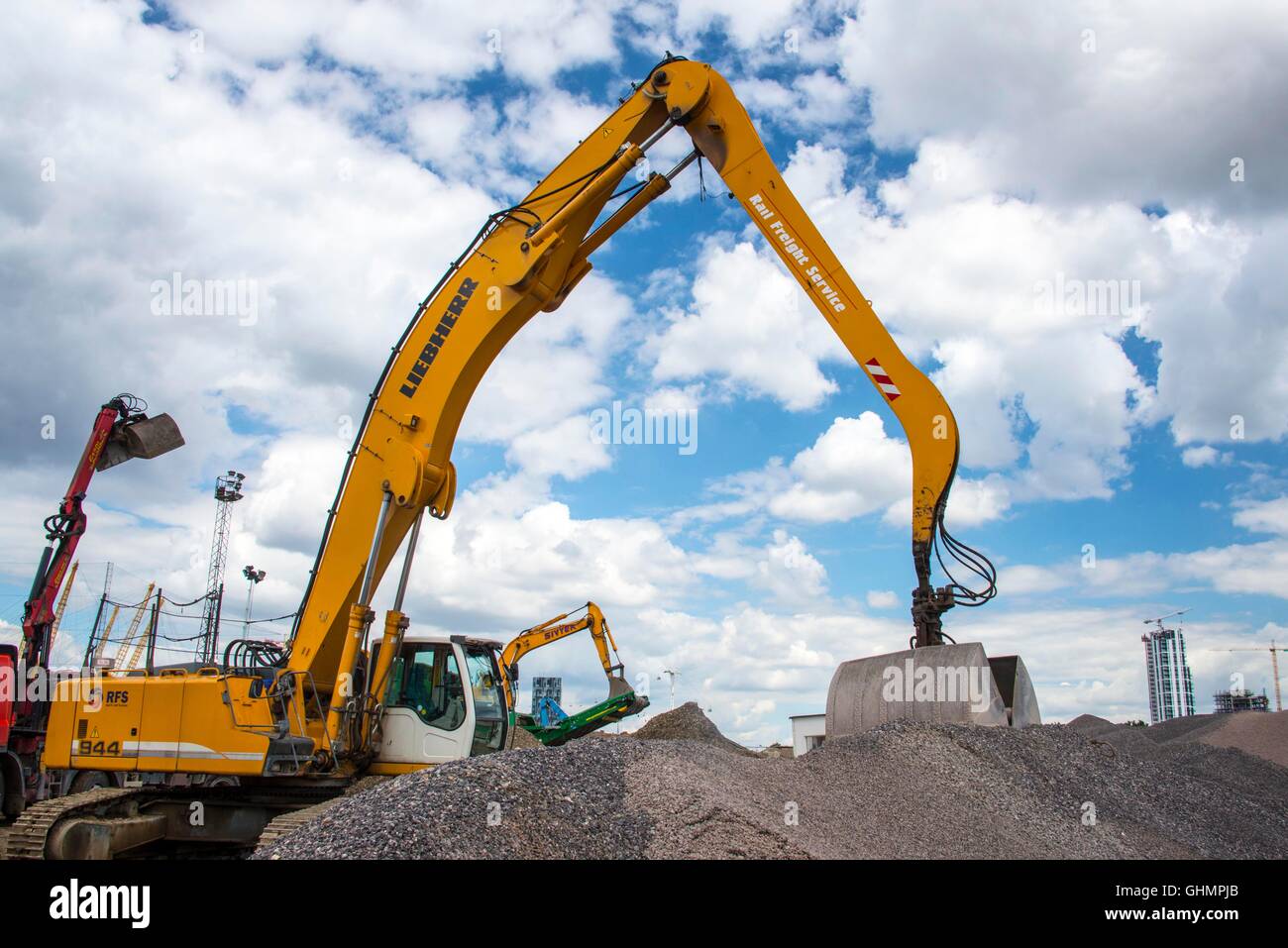 Digger moving gravel aggregates in gravel storage and sizing plant ...