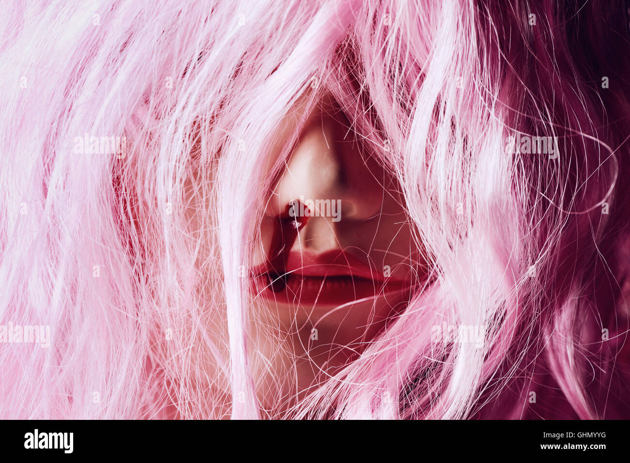 closeup of the head of a female mannequin with a pink long-hair wig bleeding from the nose Stock Photo