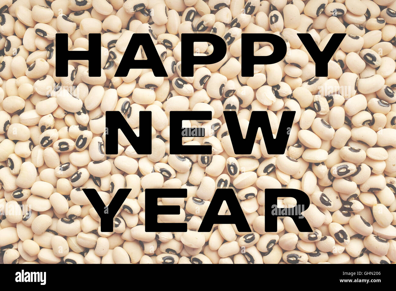 HAPPY NEW YEAR text written over a dried black eyed beans background, food considered to bring good luck Stock Photo