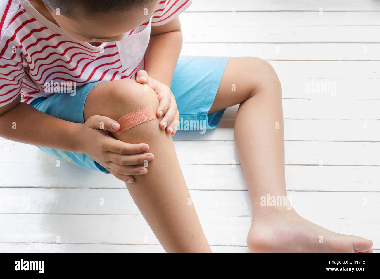 Children wound or The boy had an accident sitting on wooden white background.Top view and Stock Photo