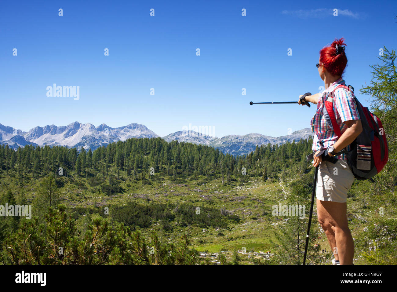 Woman hiker shows the mountain peak Stock Photo - Alamy