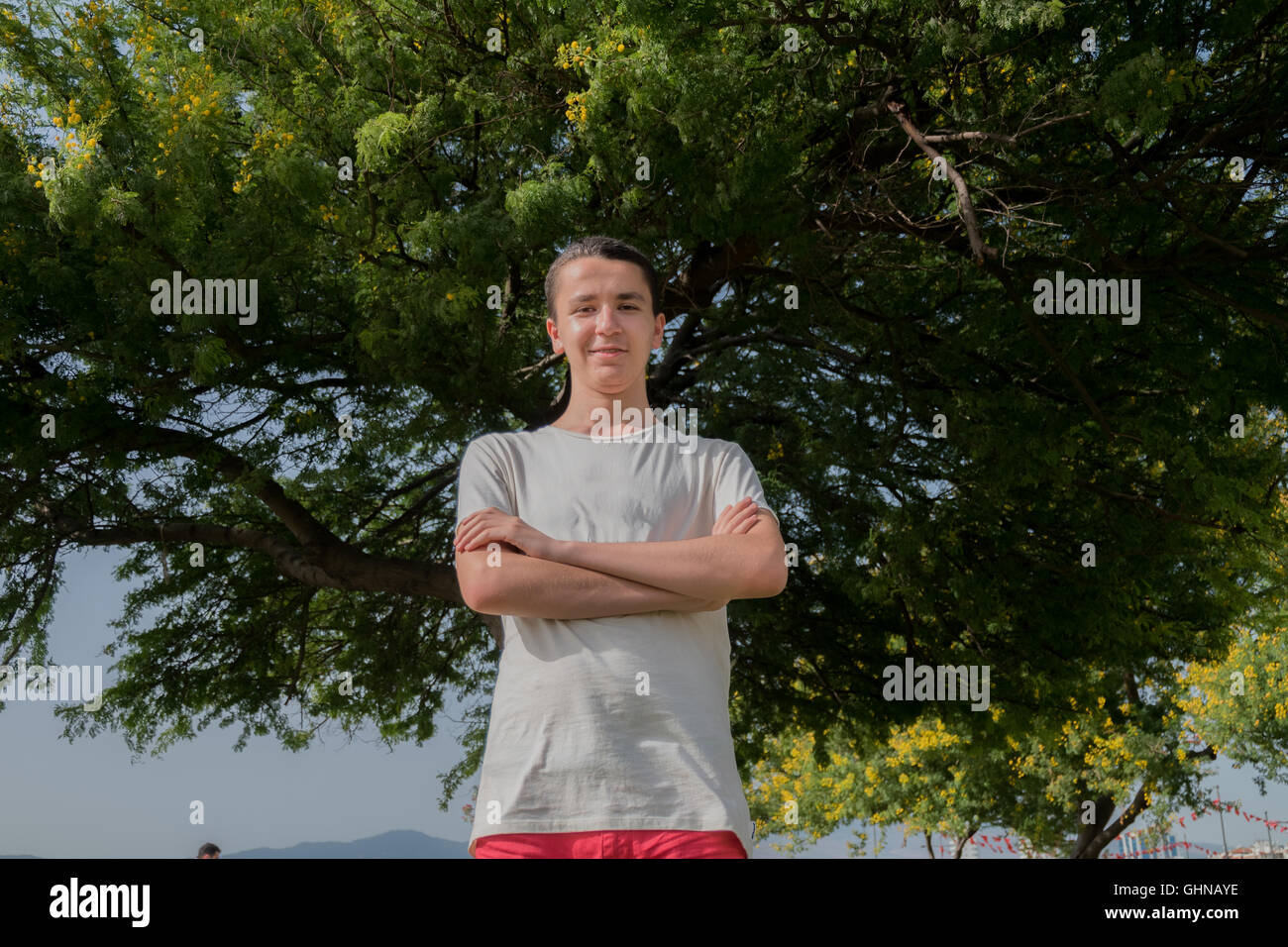 Portrait of young handsome man standing in front of a tree Stock Photo