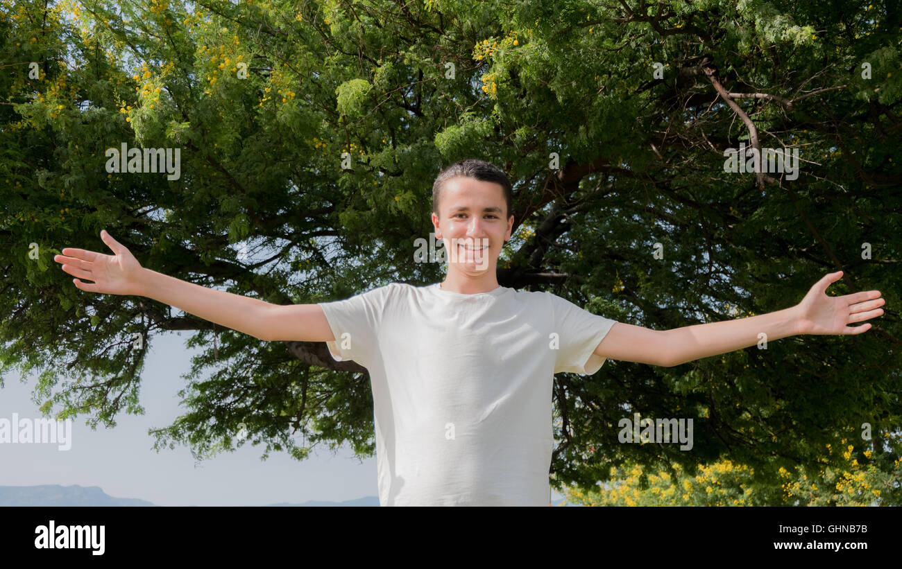 Portrait of young handsome man standing open in front of a tree Stock Photo