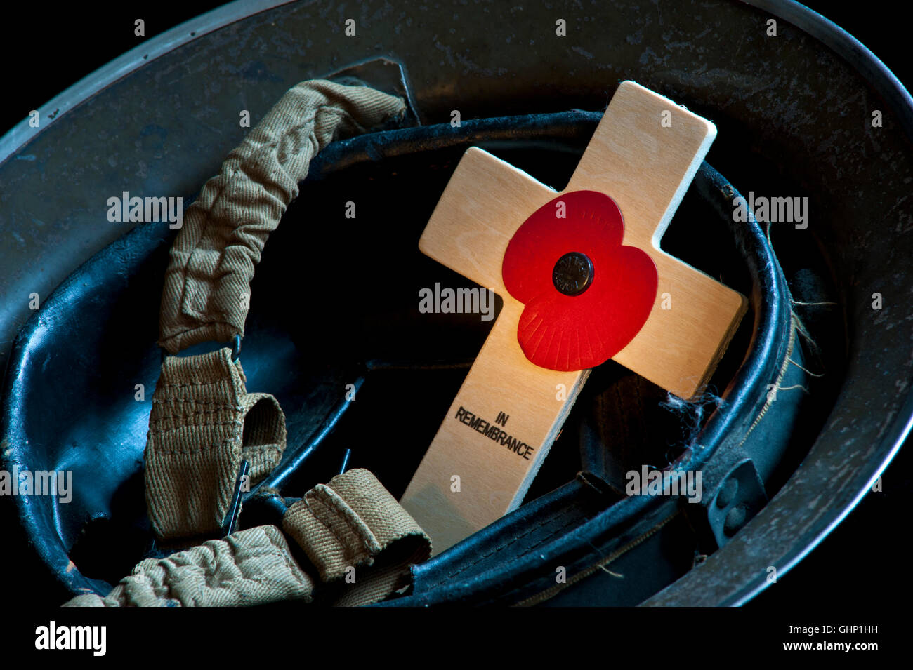 REMEMBRANCE POPPY CROSS Evocative study of WW2 original 1939 army soldier tommy military helmet with Remembrance Day poppy cross UK Stock Photo