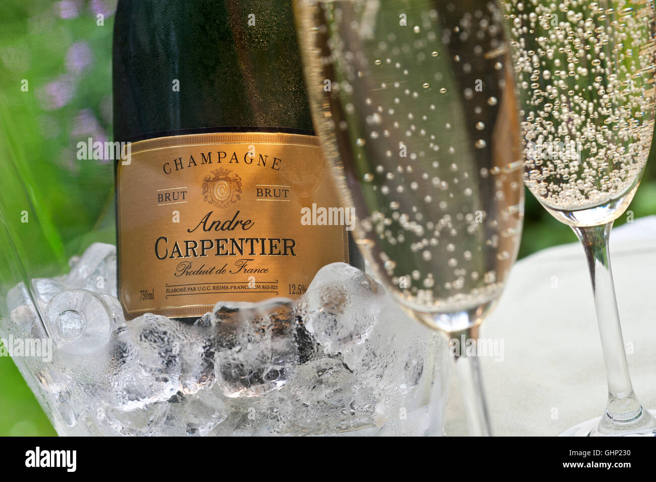 Close-up on freshly poured glasses of Andre Carpentier Champagne with bottle iced wine cooler behind on alfresco terrace table Stock Photo