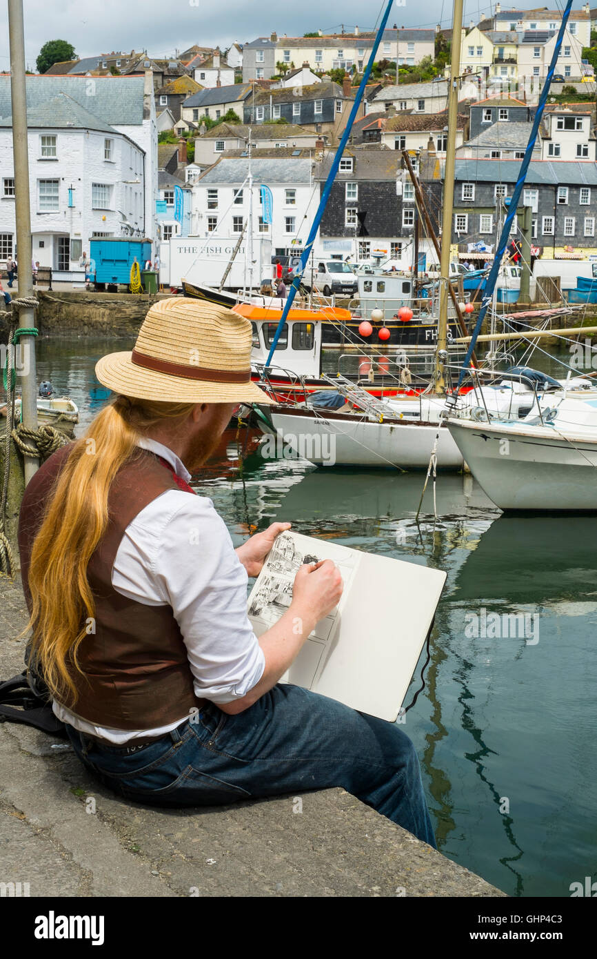 An artist sketching beside Mevagissey Harbour, Cornwall, England, UK Stock Photo
