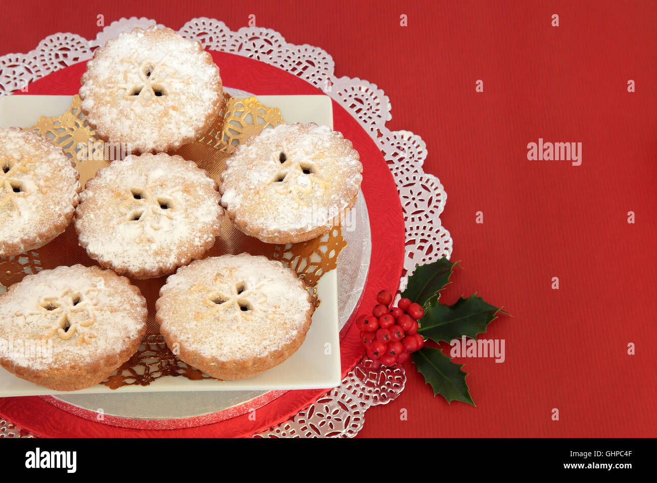 Mince pie christmas cakes with holly over red background with copy ...
