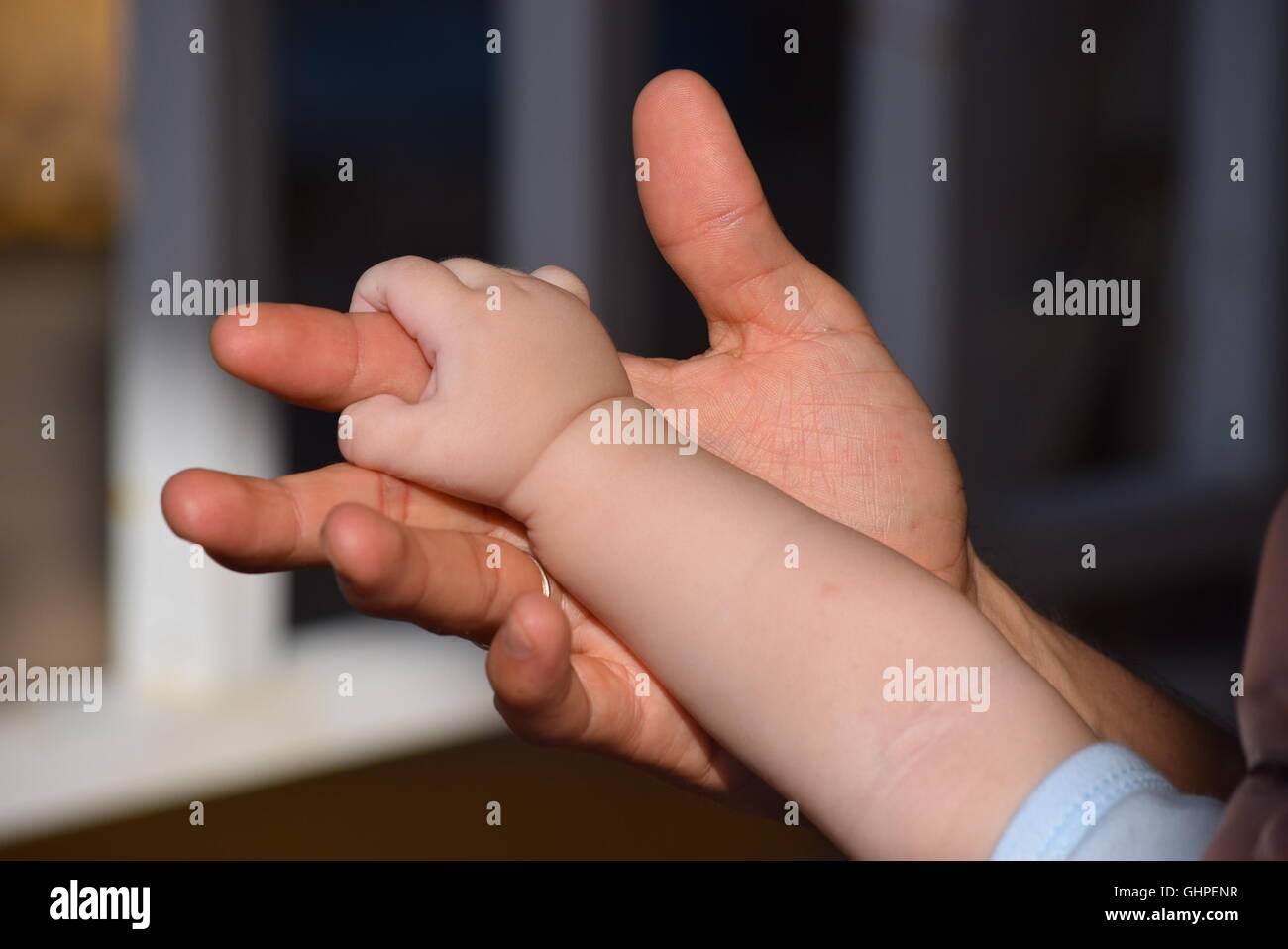 Baby holding hands with his father Stock Photo