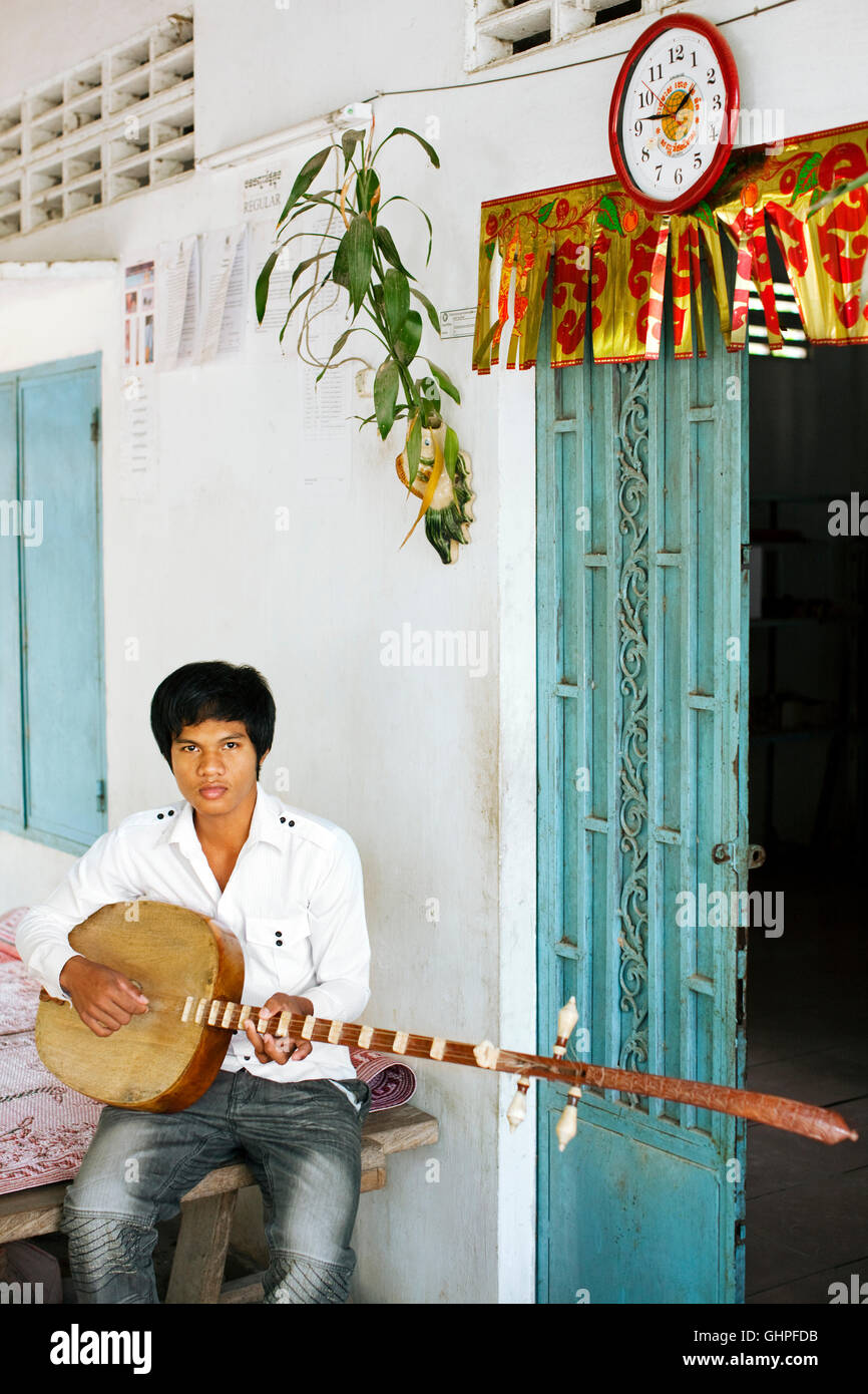 A Classical wedding music student sits holding a Chapei dang weng instrument. Bati District Takeo Province.Cambodia Stock Photo