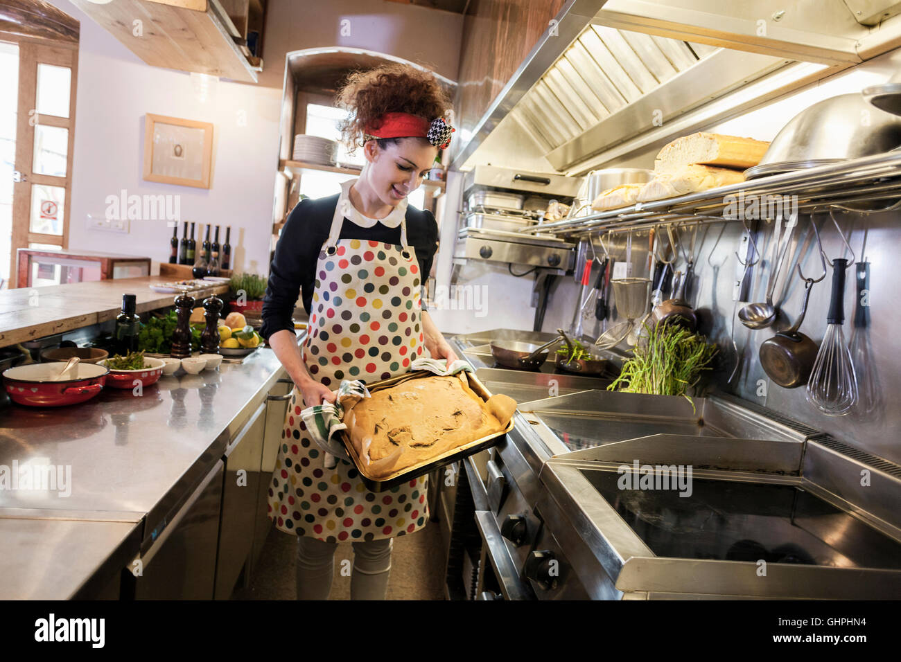 Female cook holding baking sheet in commercial kitchen Stock Photo