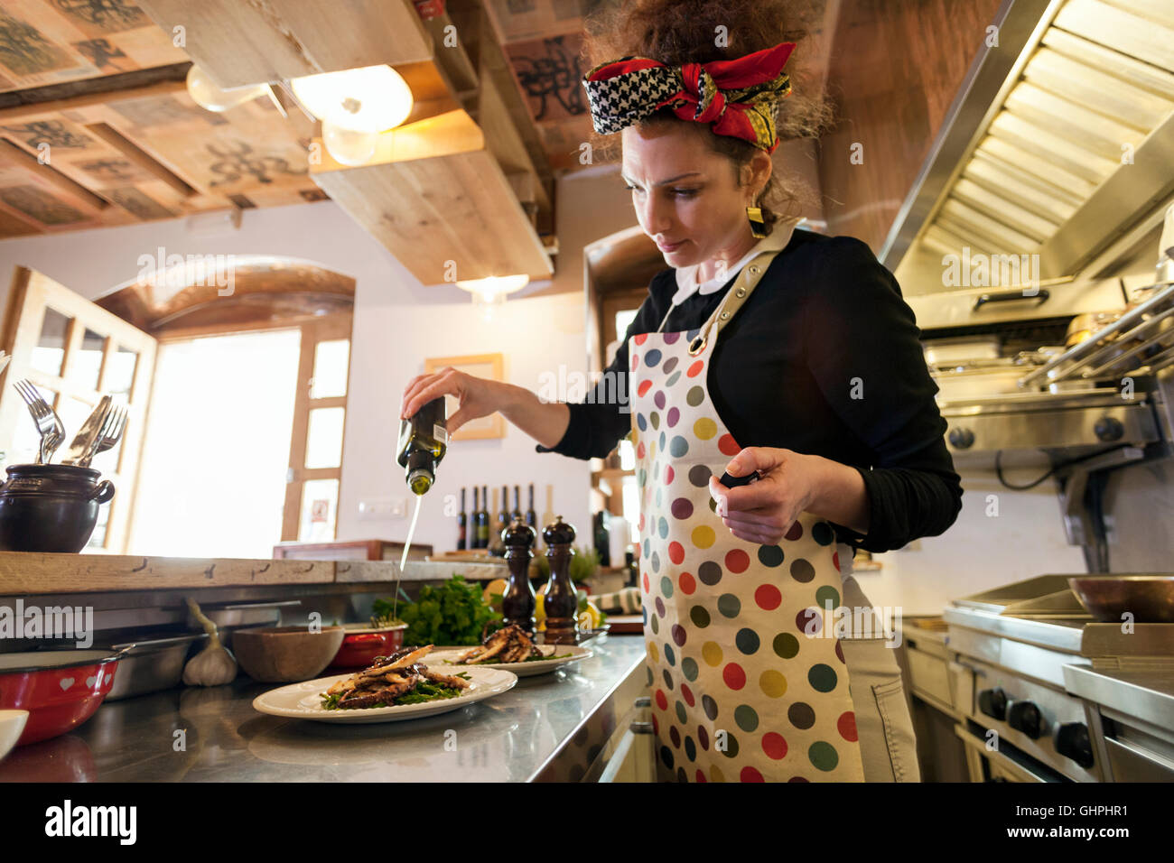 Female cook in restaurant seasoning food on plates Stock Photo