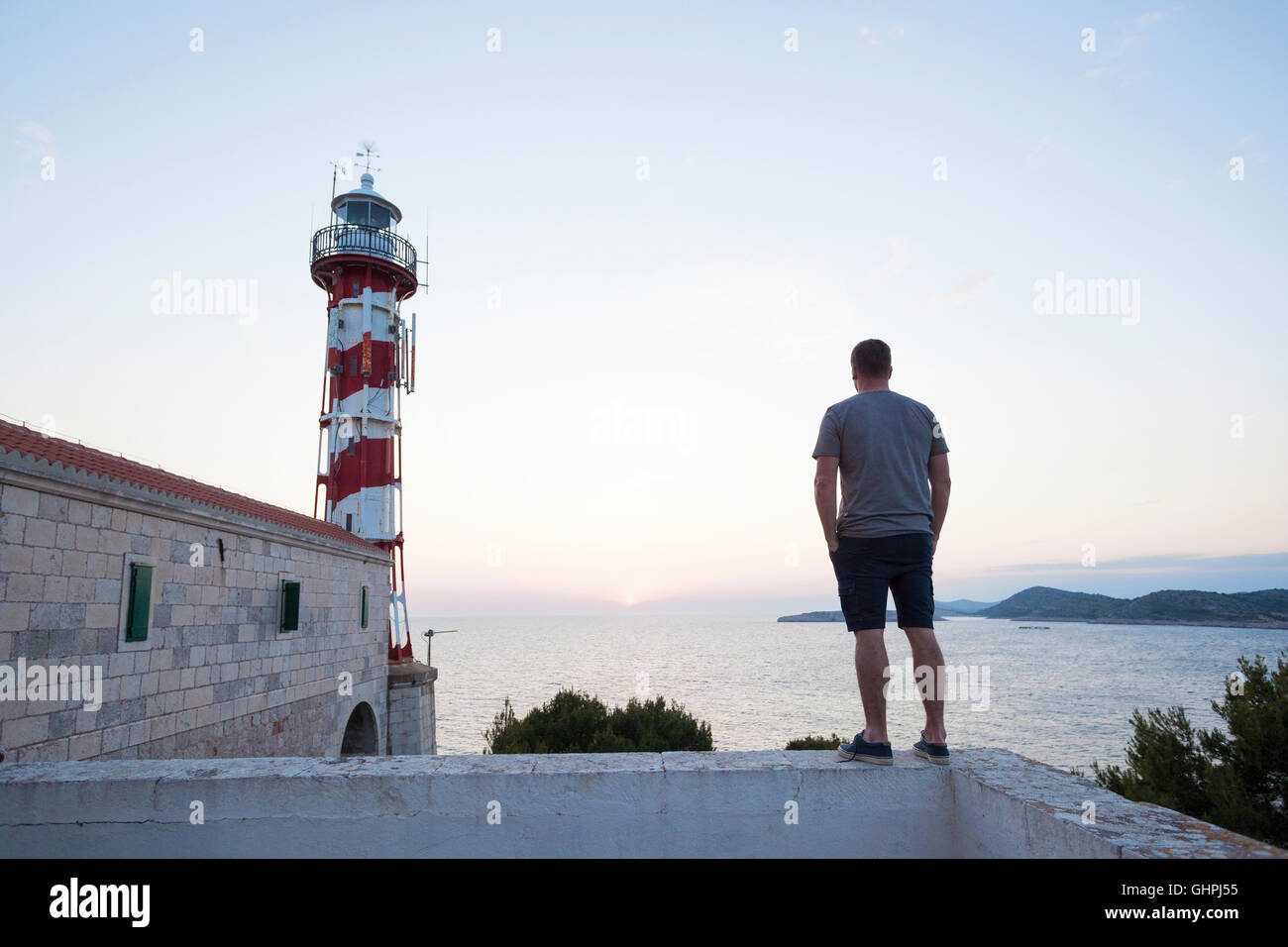 Young man near lighthouse overlooking sea Stock Photo