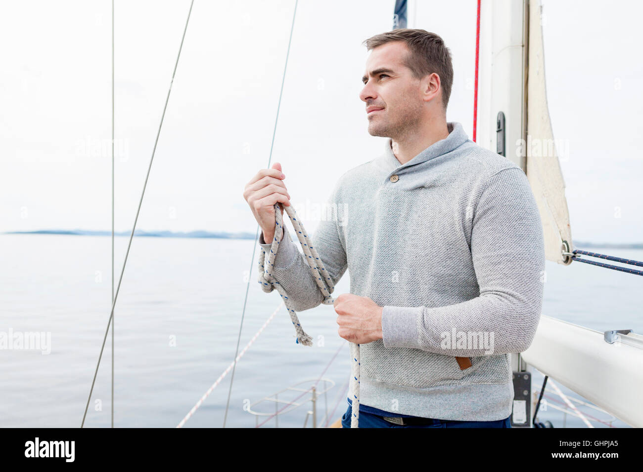 Man on yacht curling up rope Stock Photo