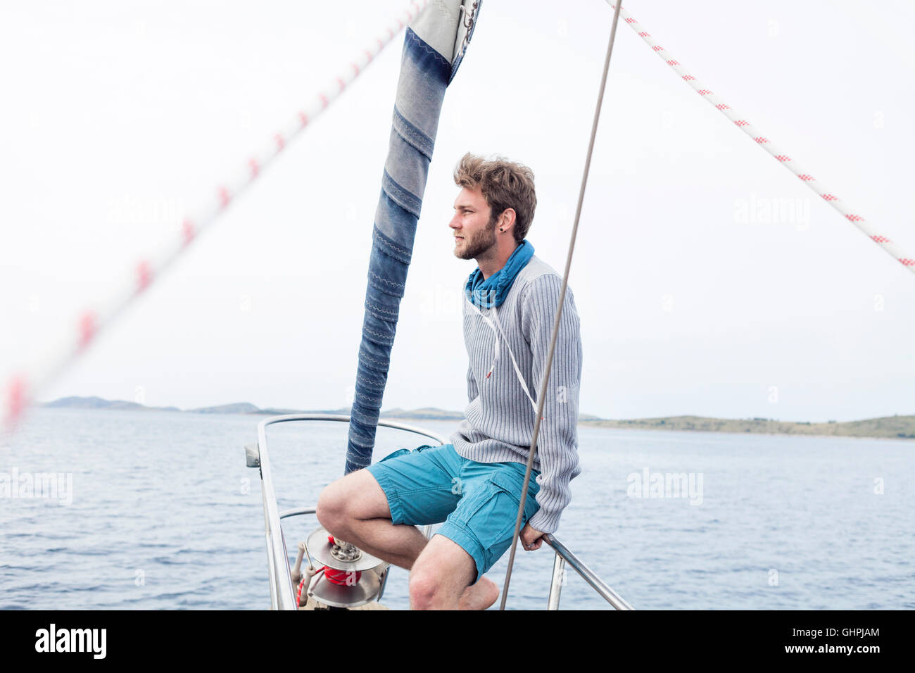 Young man sits on bow of yacht day dreaming Stock Photo