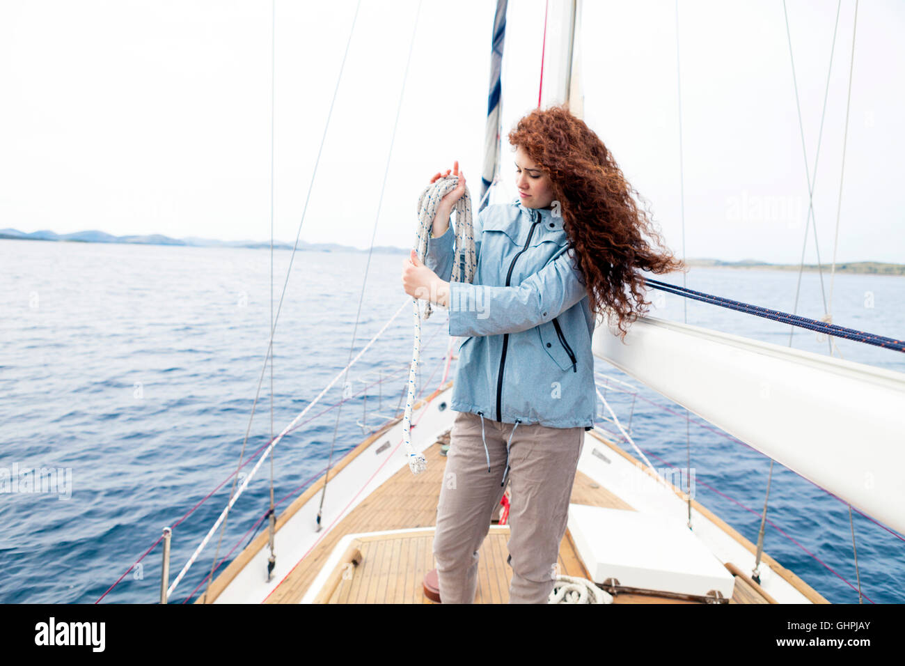 Young woman on yacht curling up rope Stock Photo