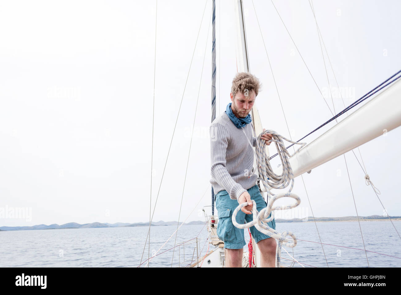 Young man on yacht curling up rope Stock Photo