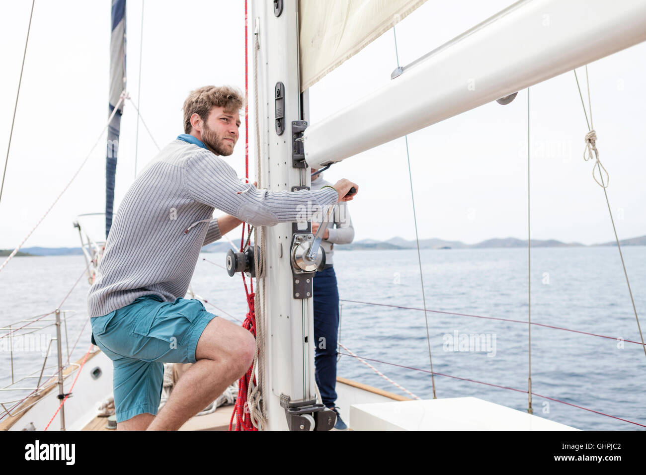 Two men pulling on rope on yacht Stock Photo