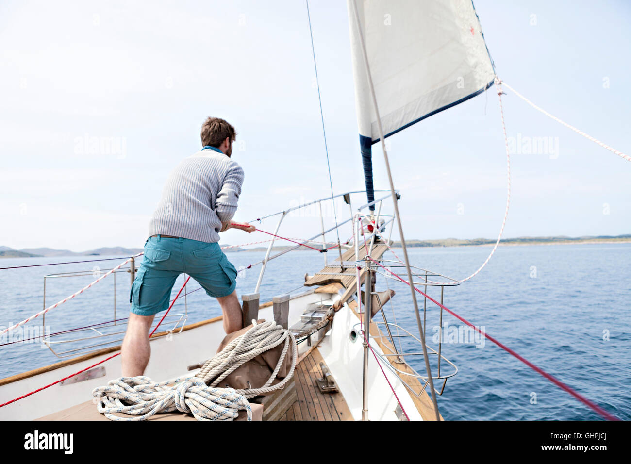 Man pulling on rope on yacht Stock Photo